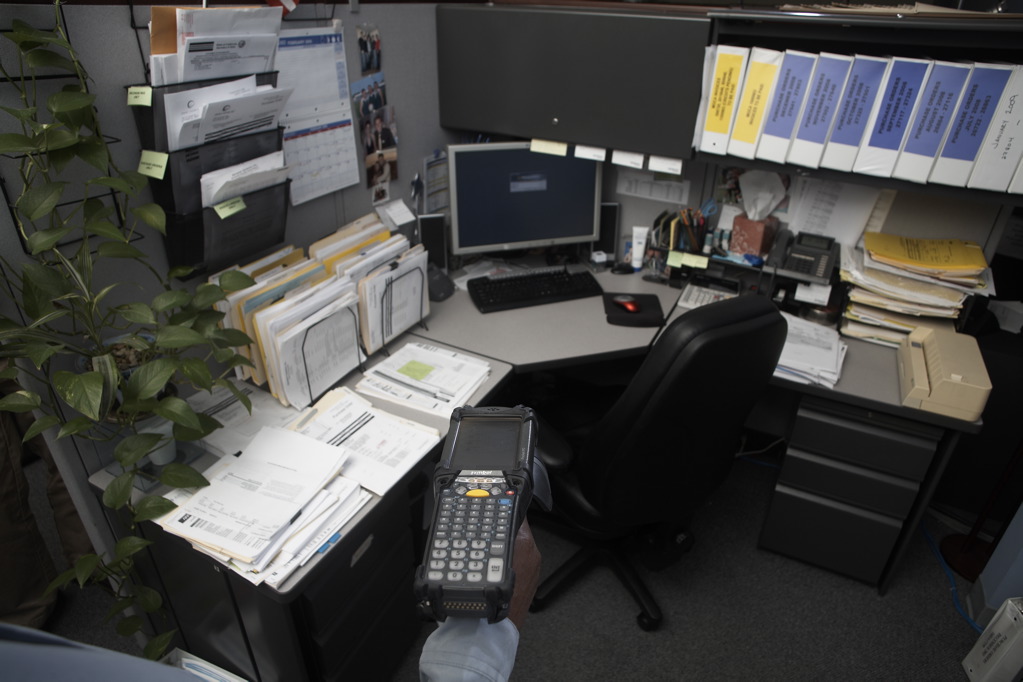 Handheld RFID reader scanning tagged file folders in an office