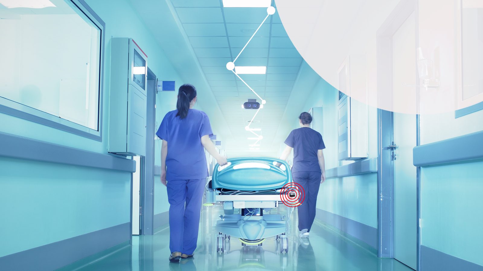 Clinicians moving a patient bed down a hospital corridor