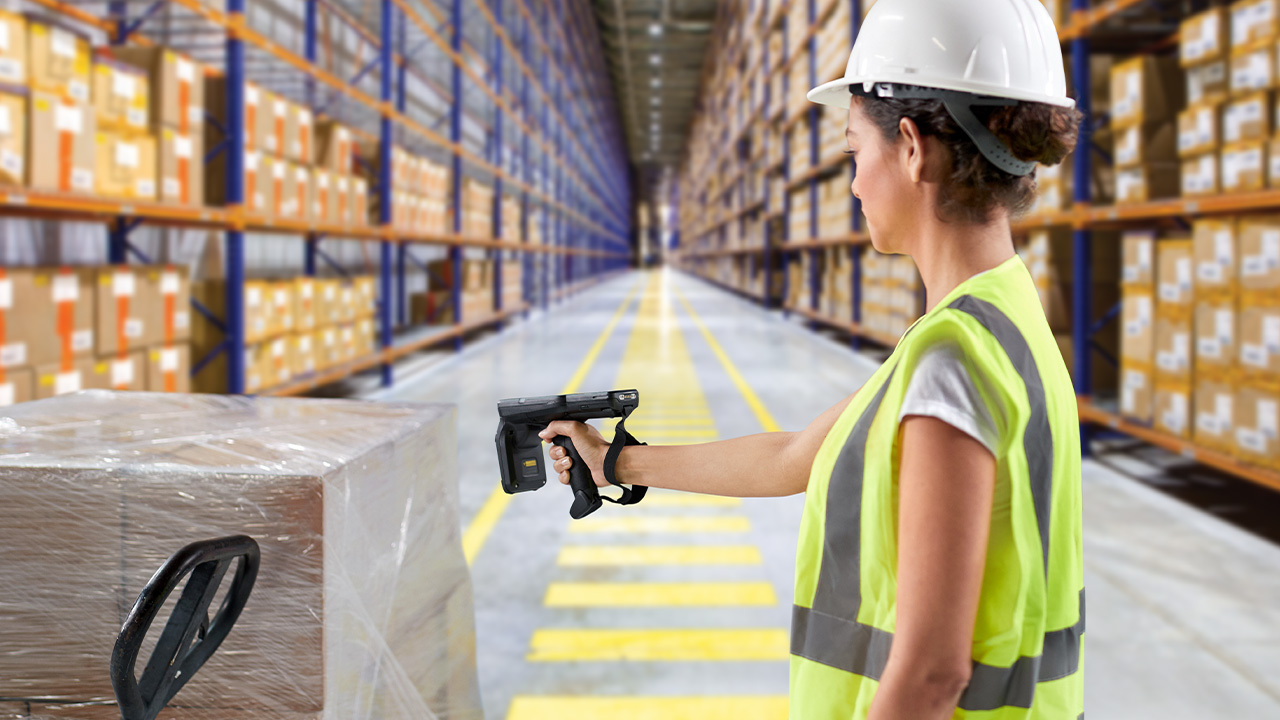 Worker scanning a wrapped pallet with a handheld RFID reader in a warehouse